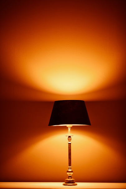 lámpara interior con luz cálida contra fondo de pared de yeso
 - Foto, Imagen