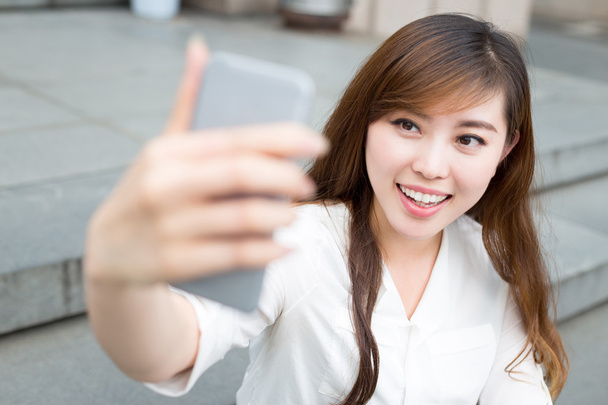 Femme utilisant un téléphone portable pour prendre selfie
  - Photo, image