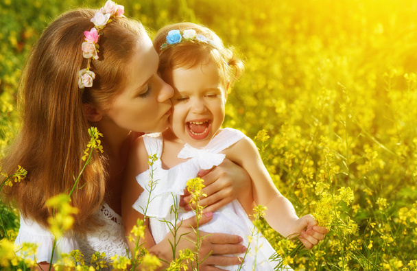 happy family in summer meadow, mother kissing little daughter ch - Foto, afbeelding