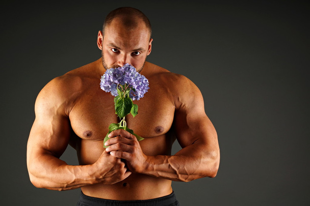 Muscle man holds blue hydrangea - Foto, imagen