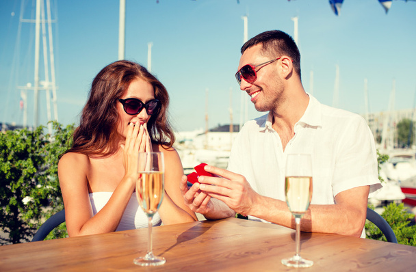 couple souriant avec champagne et cadeau au café
 - Photo, image