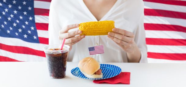 женщина держит кукурузу с хот-догом и колой
 - Фото, изображение