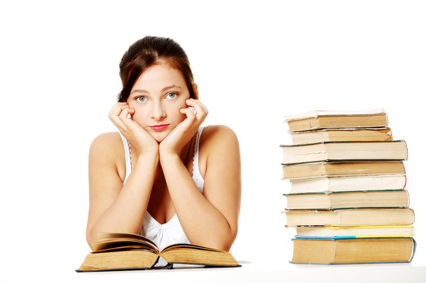 Young girl holding her head and sitting with books. - Foto, Bild