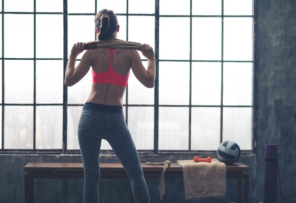 Rear view of fit woman holding towel across shoulders in gym - Foto, Bild
