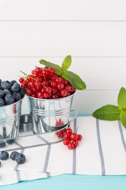 Red currants and blueberries in small metal buckets - Foto, Bild