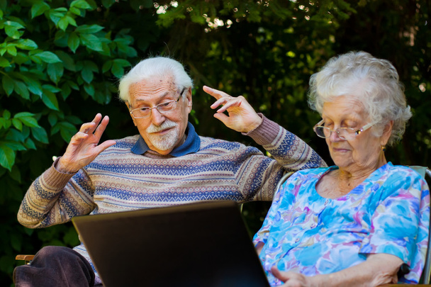 Пожилая пара веселится с ноутбуком на открытом воздухе
 - Фото, изображение