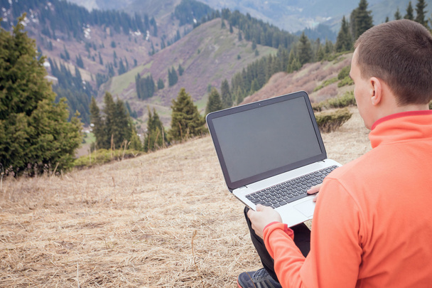 man uses laptop remotely at mountain - Fotó, kép