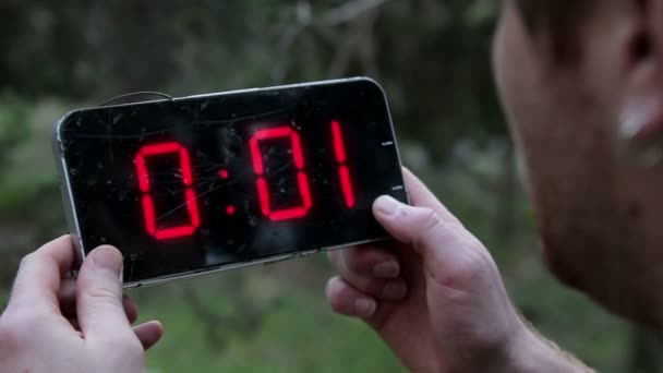 Homem segurando um relógio digital quebrado e olhando para isso o tempo congelado nele
 - Filmagem, Vídeo