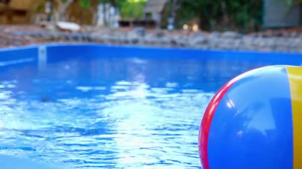 Barevný plážový míč vhozen do vody v bazénu - Záběry, video