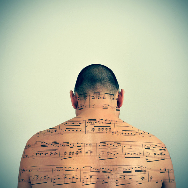 Homem com uma partitura musical estampada nas costas
 - Foto, Imagem