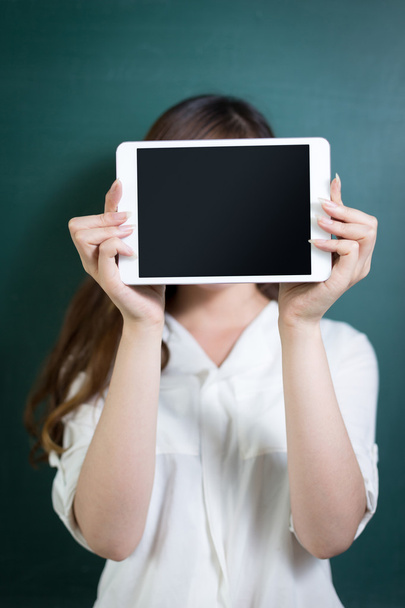 woman holding tablet in front of blackboard - Foto, afbeelding