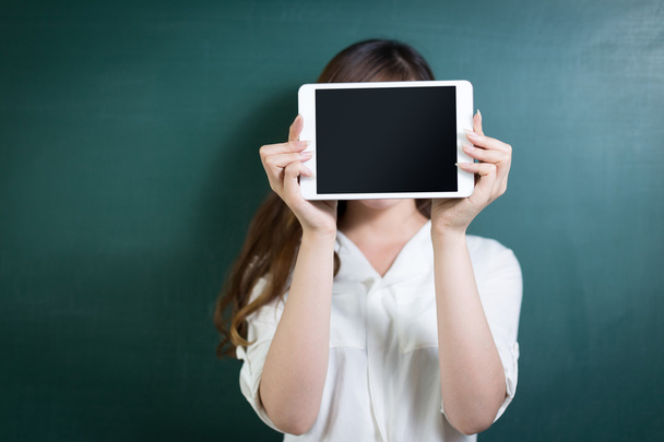 woman holding tablet in front of blackboard - Foto, afbeelding