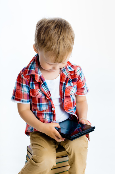 boy sitting on a pile of books with tablet computer - Photo, Image