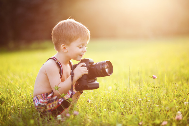 Little boy holding a photo camera in a sunny park - Foto, imagen