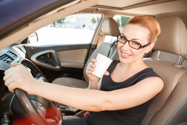 Smiling businesswoman in car with cup of coffee - Fotografie, Obrázek