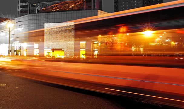 Sentiers lumineux de bus à grande vitesse et flous dans le paysage nocturne du centre-ville
 - Photo, image