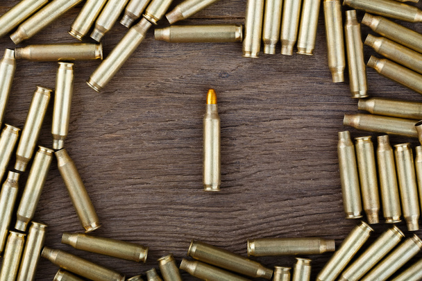 M-16 bullet on wooden table close-up. - 写真・画像