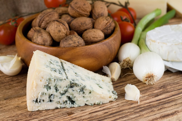 Porção de queijo azul Niva dinamarquês ao lado de vários vegetais
 - Foto, Imagem