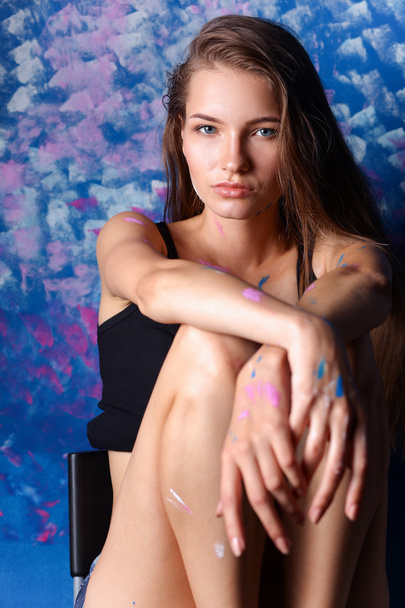 Young woman sitting near painting wall - Фото, изображение