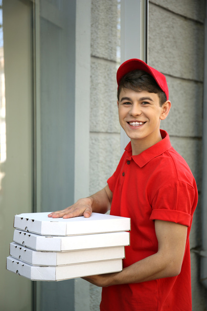 Young man delivering pizza box near house - Zdjęcie, obraz