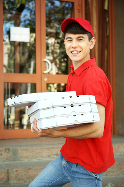 Young man delivering pizza box near house - Fotó, kép