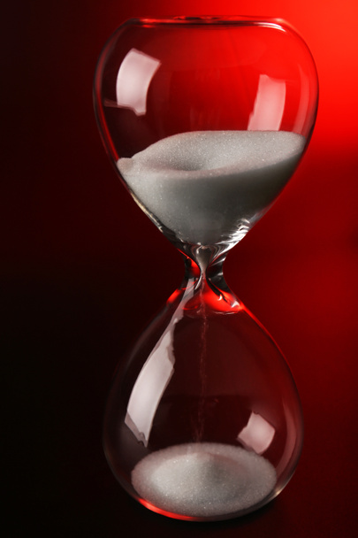 Hourglass on dark red background - Photo, Image