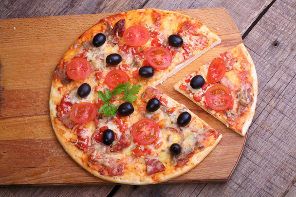 Pièce d'une pizza et pizza d'un salami, un jambon et des tomates sur
  - Photo, image