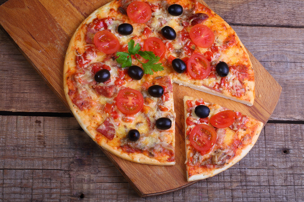 Шматочок піци та піци з салямі, шинки та помідорів на
  - Фото, зображення
