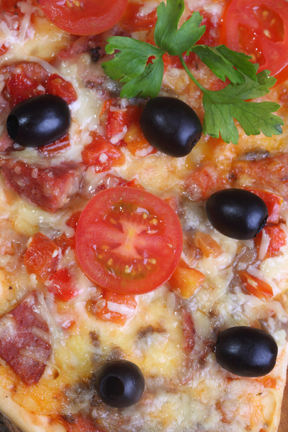  La pizza del salami, el jamón y los tomates sobre la mesa de madera
 - Foto, imagen