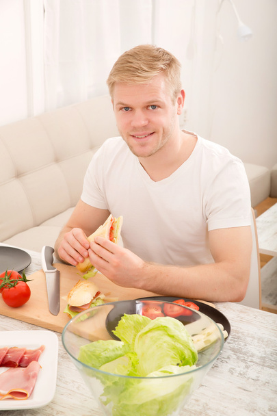 fiatal ember eszik egy szendvicset otthon - Fotó, kép