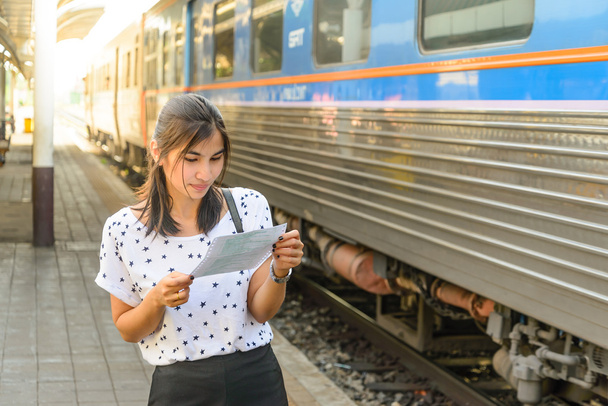 Женщина смотрит билет перед посадкой на поезд на платформе
. - Фото, изображение