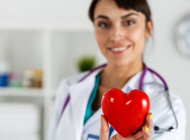 Beautiful smiling female doctor holding red heart - Photo, Image