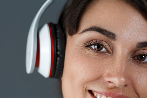 Kaunis tumma tukka hymyilevä nainen yllään kuulokkeet
 - Valokuva, kuva