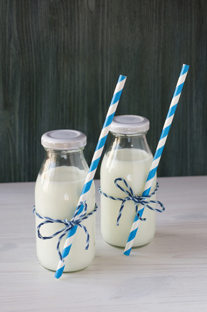Two retro bottles of milk with striped straws standing on old ta - Photo, Image