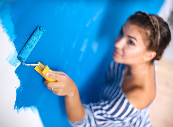 Ευτυχισμένη όμορφη νεαρή γυναίκα ζωγραφίζει στον τοίχο - Φωτογραφία, εικόνα
