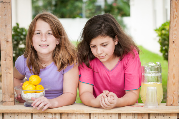 zwei gelangweilte junge Mädchen verkaufen Limonade - Foto, Bild