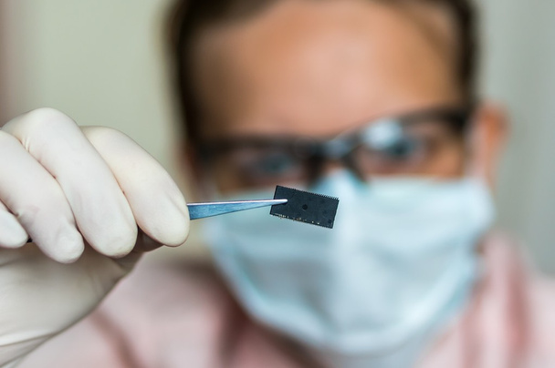 Cientista segurando e examinando chip elétrico danificado
 - Foto, Imagem