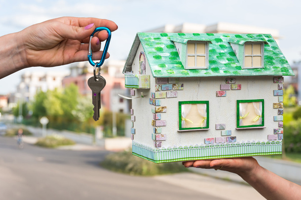 Agente immobiliare dando le chiavi di casa a un nuovo proprietario di proprietà, che sta tenendo casa modello di carta
 - Foto, immagini