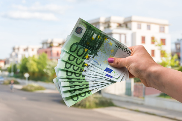 Покупатель недвижимости, держащий банкноты евро и покупающий красивый дом
 - Фото, изображение