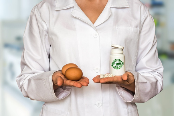 Jeune médecin tenant des œufs et bouteille de pilules avec des vitamines
 - Photo, image