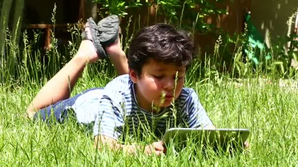 aranyos kisfiú tabletta segítségével a fűben - Felvétel, videó