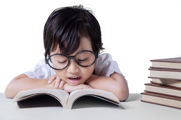 Little girl reads textbook on desk - Foto, Imagen