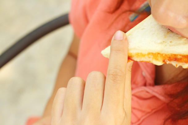 Γυναίκα τρώει ένα σάντουιτς με ζαμπόν και τυρί. - Φωτογραφία, εικόνα