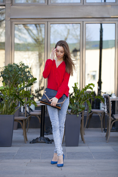 Young beautiful girl in blue jeans and red shirt on the backgrou - Fotoğraf, Görsel