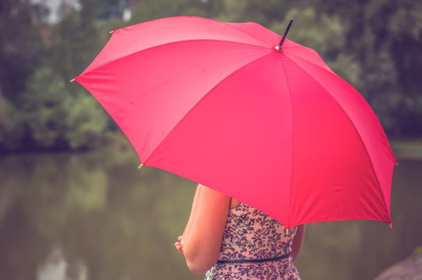 Tyttö punainen sateenvarjo lähellä lampi
 - Valokuva, kuva
