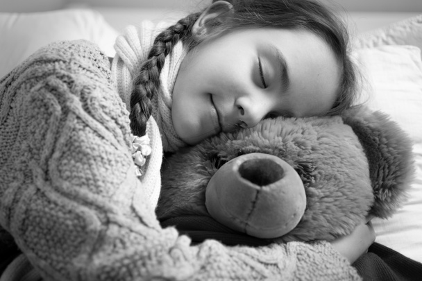 black and white portrait of cute dreaming girl hugging teddy bea - Photo, Image