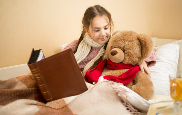 Portrait of brunette girl telling story to teddy bear at bed - Φωτογραφία, εικόνα