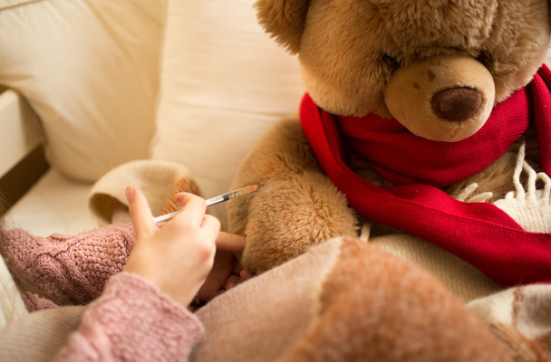 Closeup of little girl doing injection to sick teddy bear - Foto, afbeelding