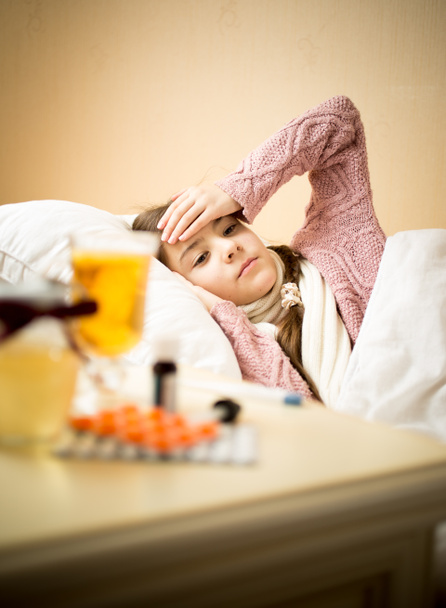 sick girl lying in bed next to table table with medicines - Zdjęcie, obraz