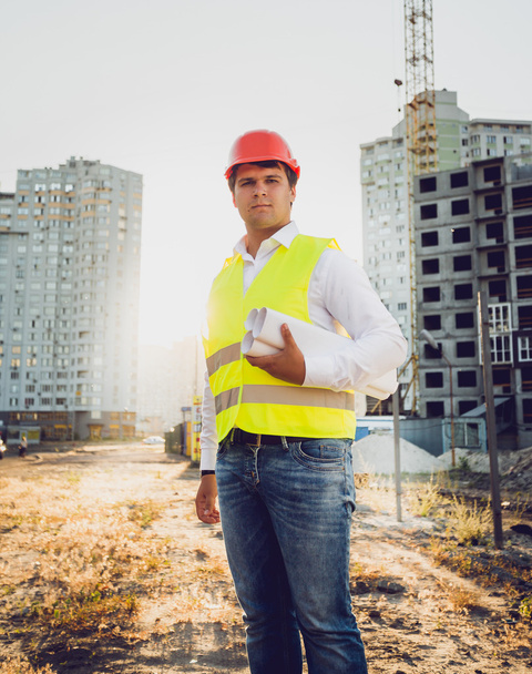 Toned photo of engineer posing against building site at sunset - Photo, Image